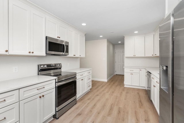 kitchen with recessed lighting, stainless steel appliances, light wood-style floors, and white cabinets