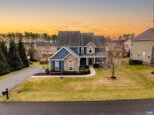 craftsman-style house featuring stone siding, board and batten siding, driveway, and a yard