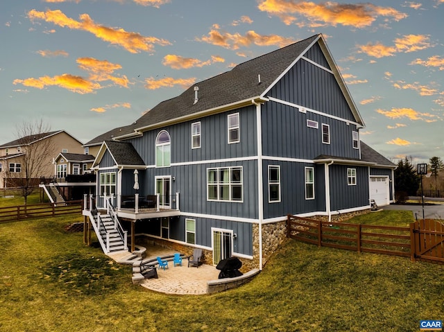 back of house at dusk with stairs, roof with shingles, and fence