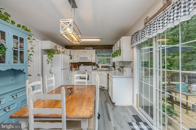 kitchen with white appliances, white cabinets, and light wood-type flooring