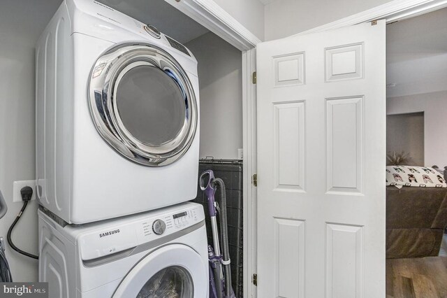 washroom with wood-type flooring and stacked washer and clothes dryer