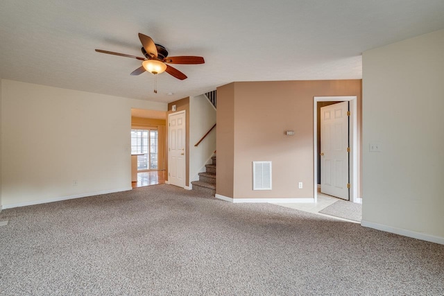 empty room with stairs, baseboards, visible vents, and light colored carpet