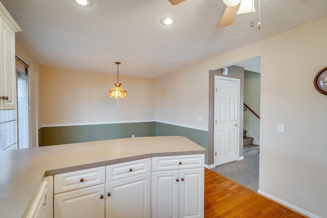 kitchen featuring light countertops, white cabinets, decorative light fixtures, and a peninsula