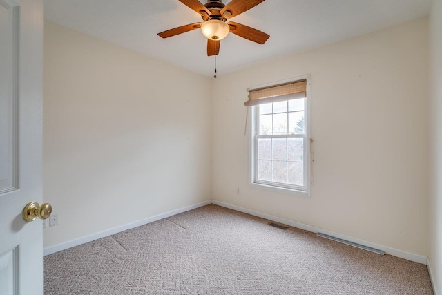 carpeted spare room with a ceiling fan, visible vents, and baseboards