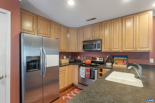 kitchen featuring visible vents, stainless steel appliances, light wood-style floors, light brown cabinets, and a sink