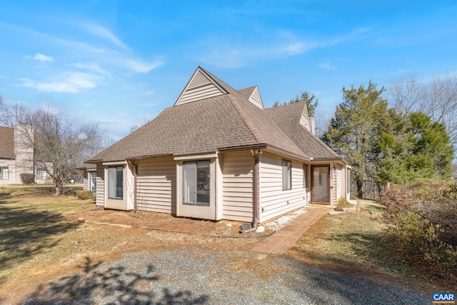 exterior space featuring roof with shingles and a front lawn