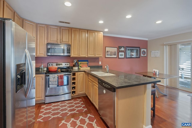 kitchen featuring dark wood finished floors, stainless steel appliances, visible vents, a sink, and a peninsula