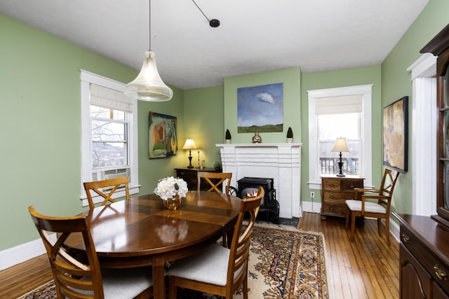 dining room with dark wood finished floors, baseboard heating, a fireplace, and baseboards