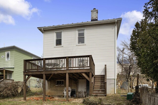 rear view of house with stairway, a wooden deck, a chimney, and fence