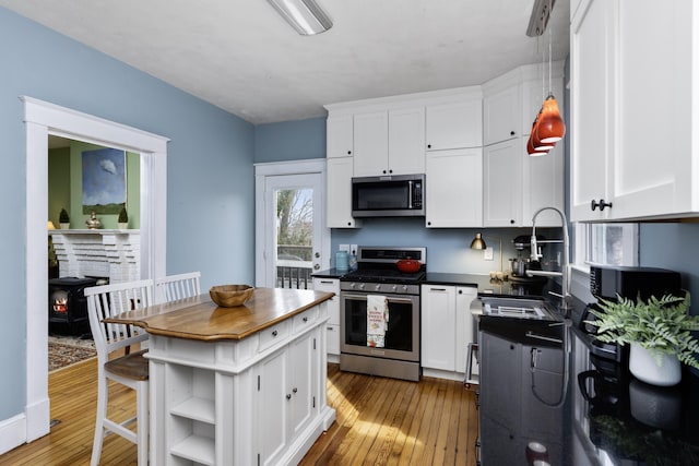 kitchen with appliances with stainless steel finishes, a wood stove, and white cabinetry