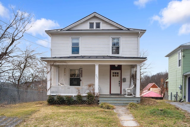 traditional style home featuring a standing seam roof, a porch, fence, a front yard, and metal roof