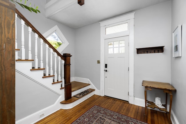 foyer entrance with stairway, wood finished floors, and baseboards