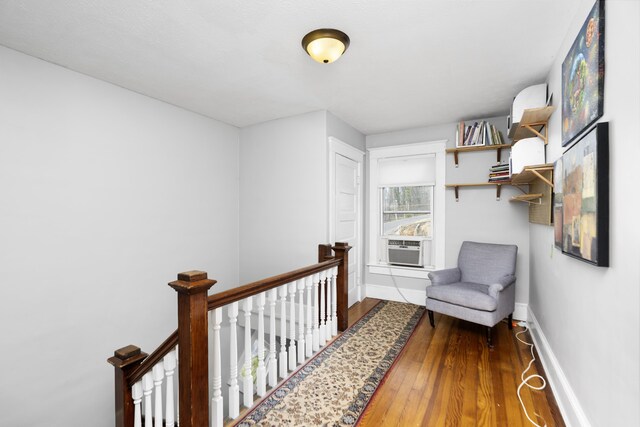 hall with wood finished floors, an upstairs landing, and baseboards