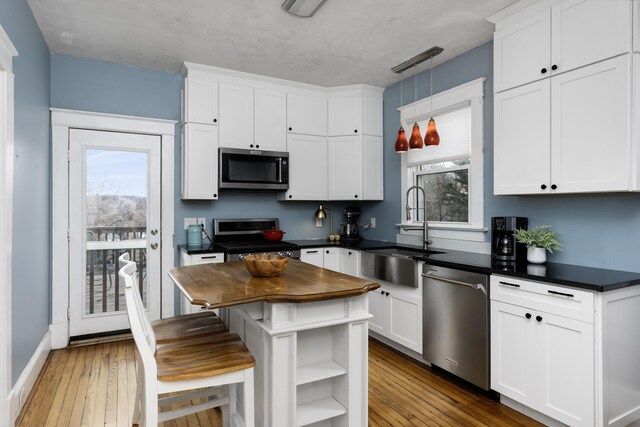 kitchen featuring a sink, appliances with stainless steel finishes, hardwood / wood-style floors, and white cabinetry