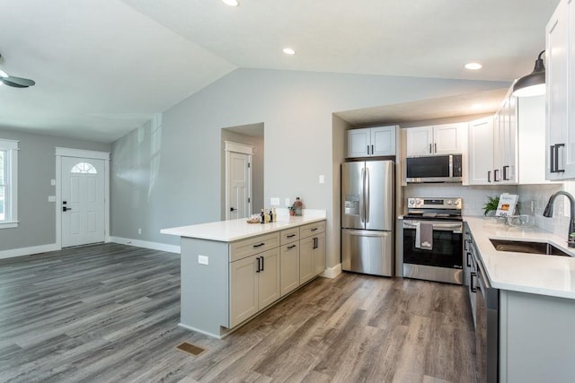 kitchen featuring sink, white cabinetry, hardwood / wood-style floors, stainless steel appliances, and kitchen peninsula