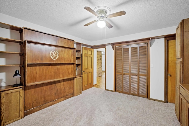 unfurnished bedroom featuring ceiling fan, a closet, light carpet, and a textured ceiling