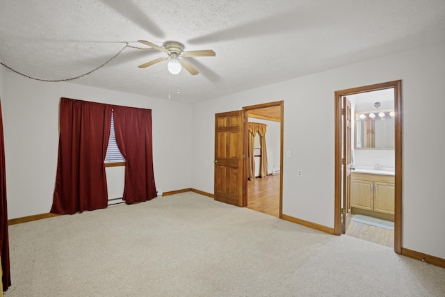 unfurnished bedroom with ensuite bath, sink, light carpet, and a textured ceiling