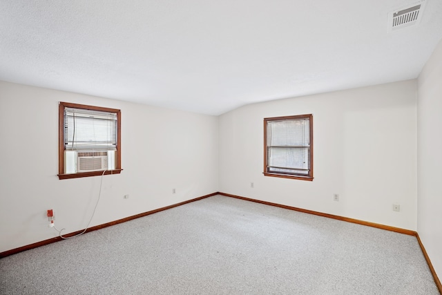 carpeted empty room featuring vaulted ceiling and cooling unit