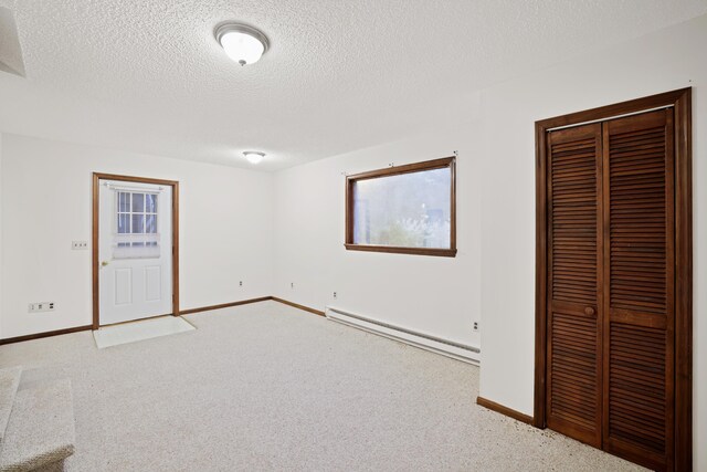 unfurnished bedroom with light carpet, a closet, a textured ceiling, and baseboard heating