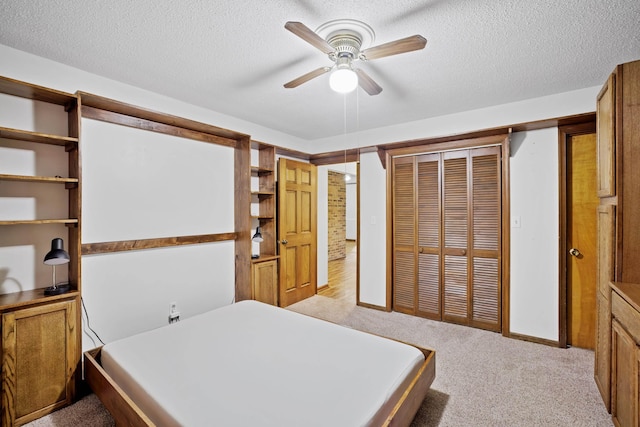 bedroom with ceiling fan, light colored carpet, a closet, and a textured ceiling