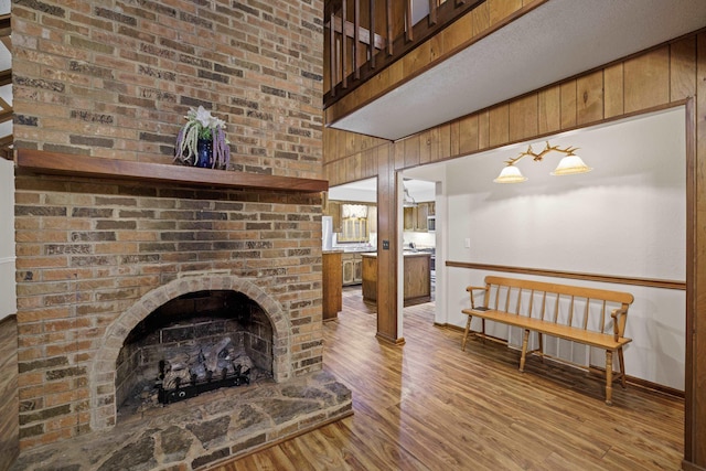 living room featuring a high ceiling, wooden walls, hardwood / wood-style floors, and a fireplace