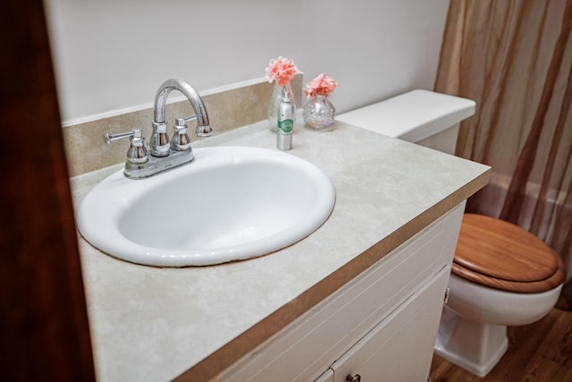 bathroom with vanity, toilet, and hardwood / wood-style floors