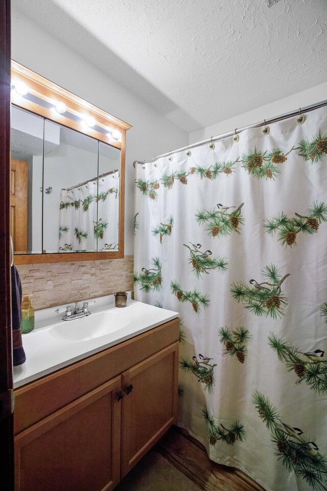 bathroom with vanity, backsplash, a textured ceiling, and walk in shower