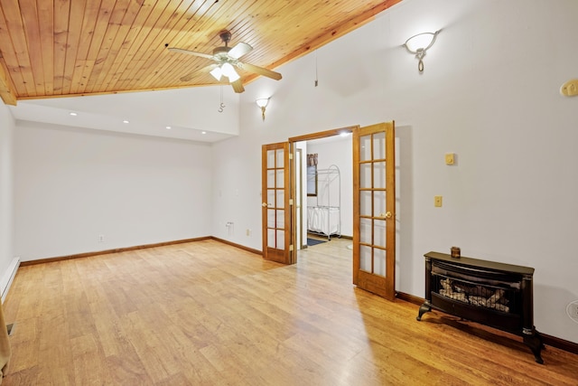 spare room with lofted ceiling, wood ceiling, light wood-type flooring, french doors, and a wood stove