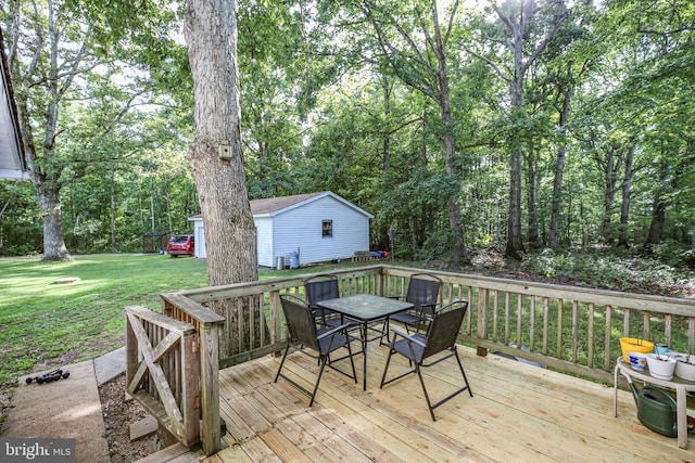 wooden deck with an outbuilding, outdoor dining area, and a yard