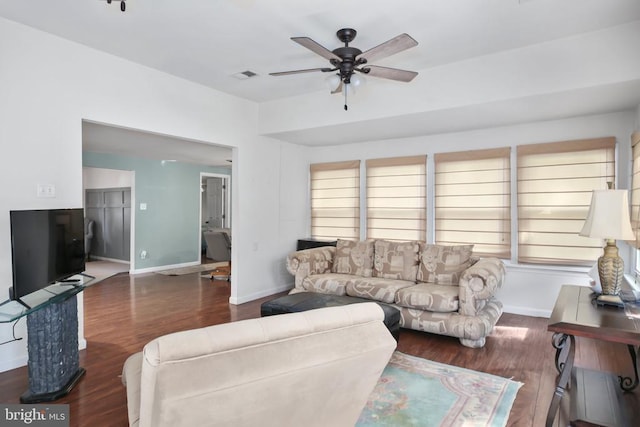 living area with a ceiling fan, visible vents, baseboards, and wood finished floors