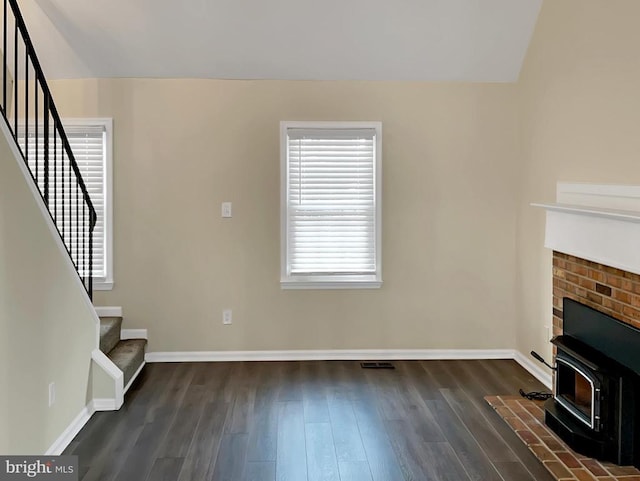 unfurnished living room featuring dark wood-type flooring and a wood stove