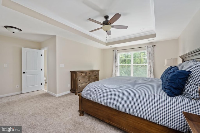 bedroom featuring ceiling fan, a tray ceiling, light colored carpet, and baseboards