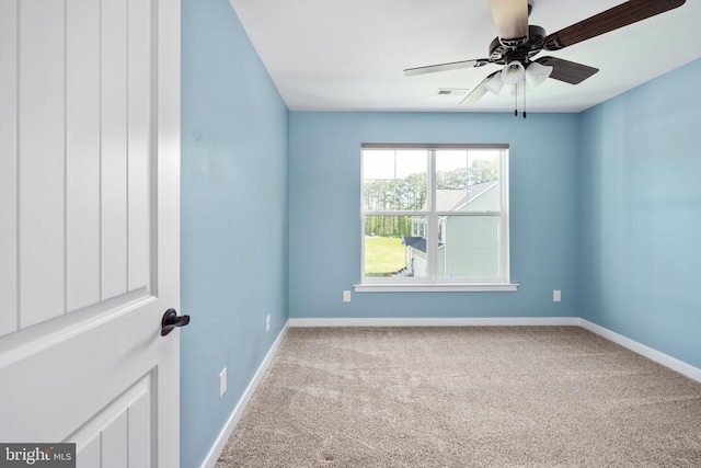 carpeted spare room with visible vents, baseboards, and ceiling fan