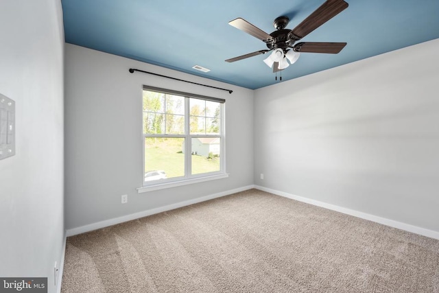 spare room with baseboards, carpet, a ceiling fan, and visible vents