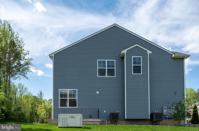 view of side of property with central AC unit and a yard