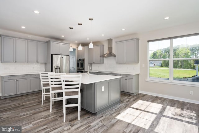 kitchen featuring black electric cooktop, gray cabinets, high end refrigerator, wall chimney exhaust hood, and wood finished floors