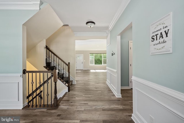 hall featuring ornamental molding, wainscoting, and wood finished floors