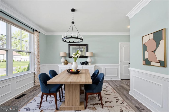 dining space featuring an inviting chandelier, ornamental molding, wood finished floors, and visible vents