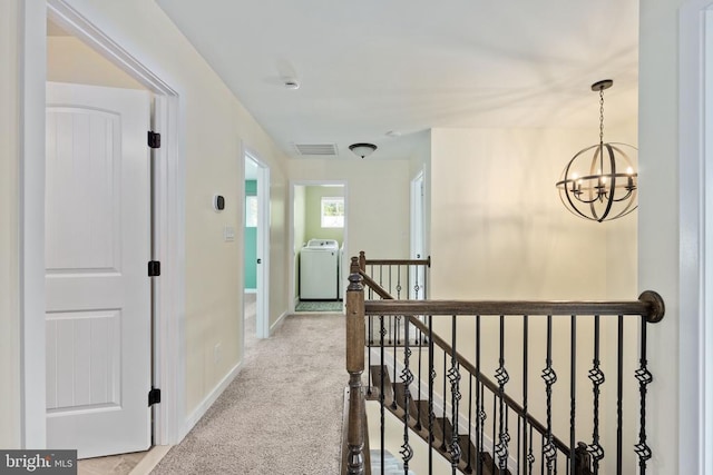 corridor with washer / dryer, baseboards, carpet, a notable chandelier, and an upstairs landing