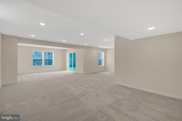 spare room featuring light carpet, recessed lighting, and baseboards