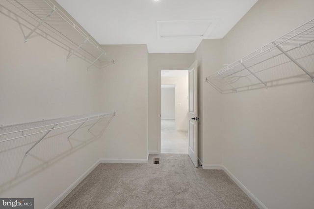 spacious closet featuring light carpet, attic access, and visible vents