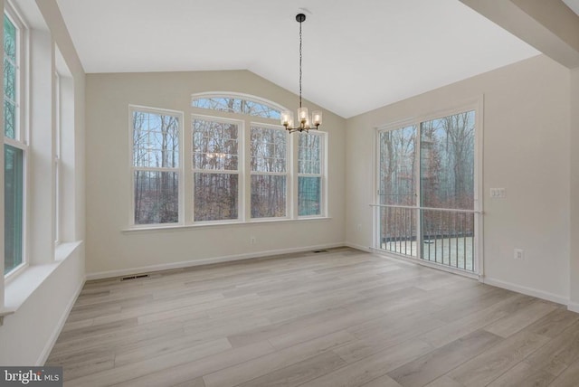 unfurnished dining area featuring light wood-style floors, vaulted ceiling, a wealth of natural light, and an inviting chandelier