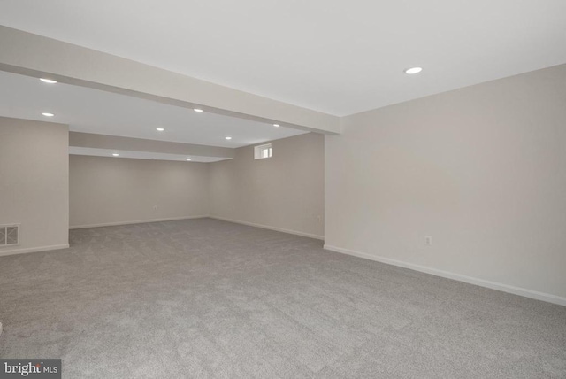 basement featuring light carpet, baseboards, visible vents, and recessed lighting