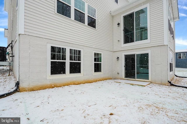 snow covered property featuring brick siding