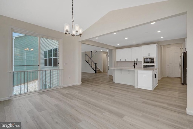 kitchen with light countertops, hanging light fixtures, appliances with stainless steel finishes, open floor plan, and white cabinets