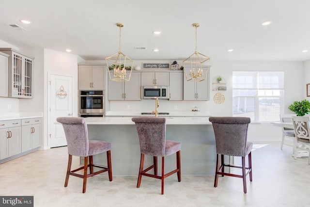 kitchen featuring a chandelier, hanging light fixtures, gray cabinetry, and stainless steel appliances