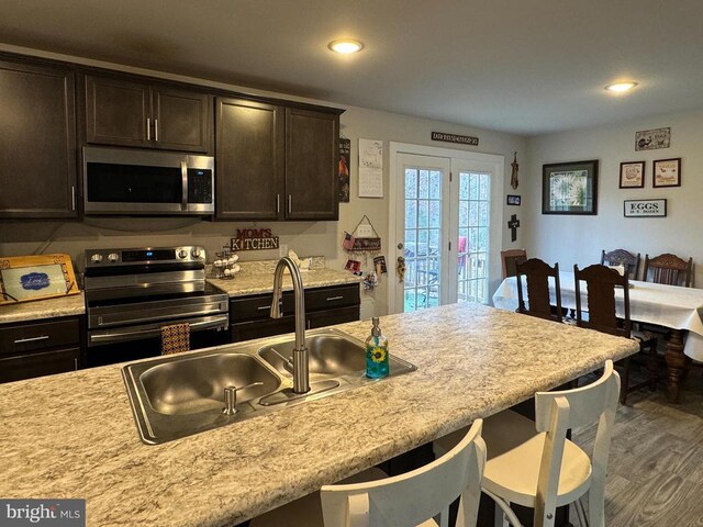 kitchen featuring appliances with stainless steel finishes, sink, dark hardwood / wood-style flooring, a kitchen breakfast bar, and dark brown cabinetry