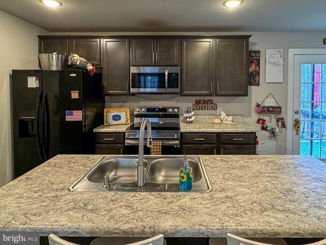 kitchen featuring dark brown cabinetry, appliances with stainless steel finishes, and a kitchen island with sink