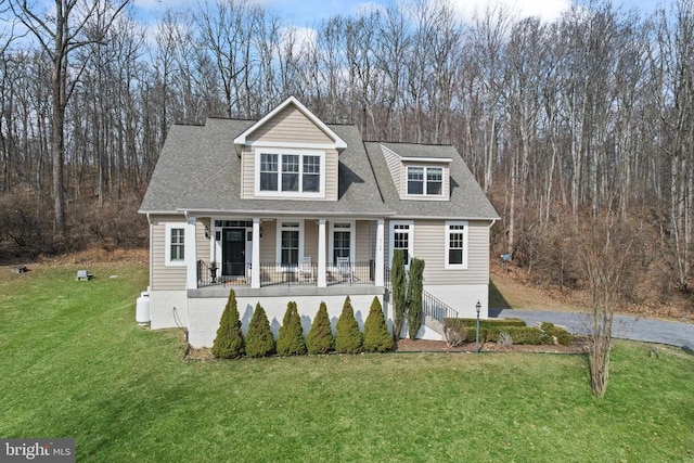 view of front of home with a front yard, covered porch, and roof with shingles