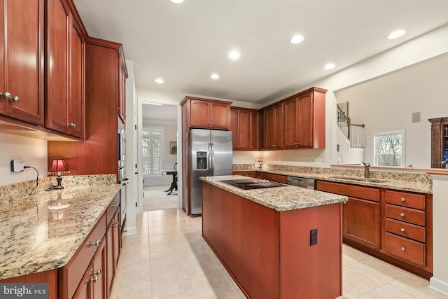 kitchen featuring plenty of natural light, a kitchen island, light stone countertops, stainless steel appliances, and a sink